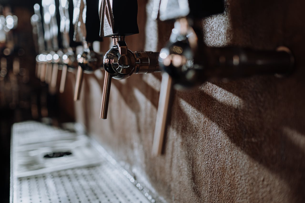 Artistic close-up of beer taps in a moody bar setting, capturing warm lighting and texture.
